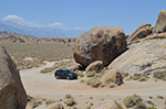 An SUV looks small compared to the rocks in the Alabama Hills.